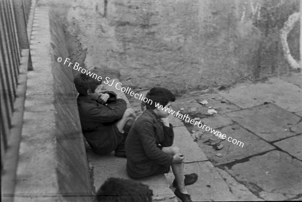 CHILDREN SITTING IN HANDBALL ALLEY